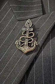 broche comportant une ancre sur un costume noir rayé. 
