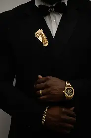 borche dorée en forme de visage sur un costume noir.